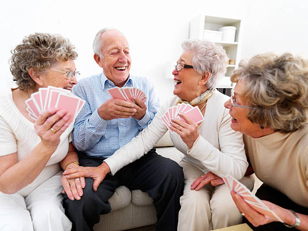 Happy senior men and women playing cards Happy senior men and women playing cards friends playing cards stock pictures, royalty-free photos & images