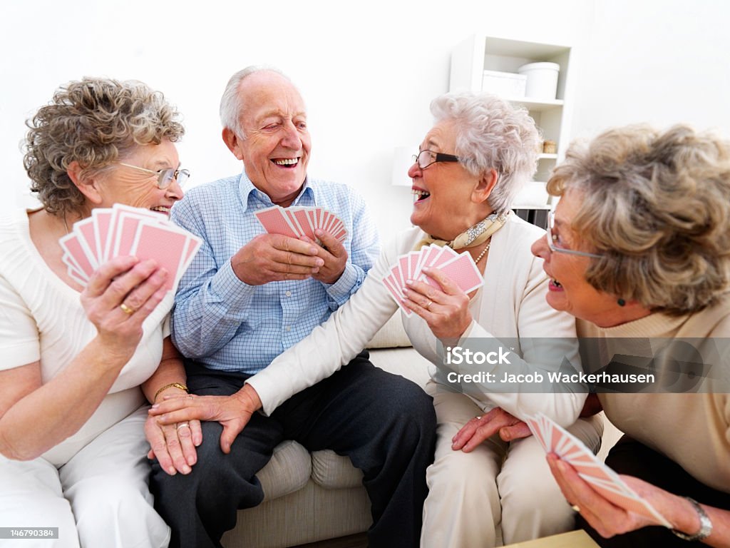 Happy senior mulheres e homens jogando cartas - Foto de stock de Terceira idade royalty-free