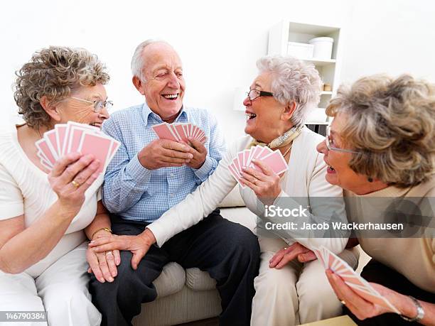 Foto de Happy Senior Mulheres E Homens Jogando Cartas e mais fotos de stock de Terceira idade - Terceira idade, Carta de baralho - Jogo de lazer, Rindo