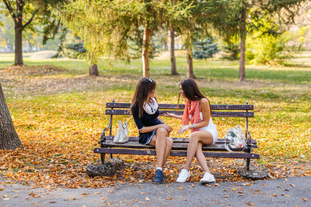 Two Beautiful female friends talking on the park bench.
