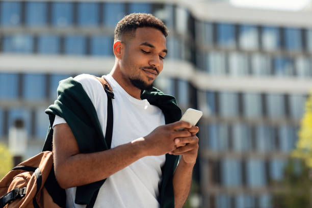 istock Modern mobile communication. Portrait of black stylish guy using smartphone outdoors, walking in urban city area 1467904629