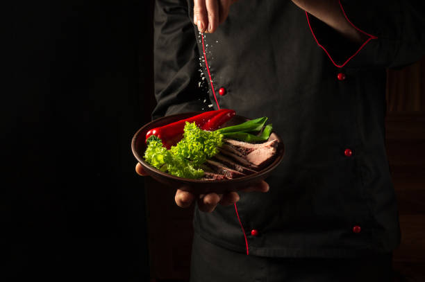 istock Grilled and sliced beef steak with grilled vegetables served on plate on black background presentation in chef hands. 1467904922