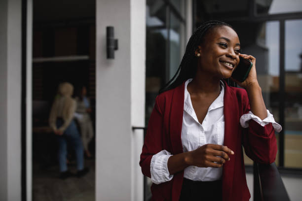 istock Talking on her phone while managing her work, a young black woman stands in her office 1467908857