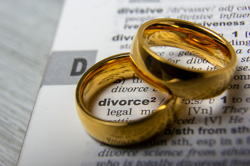 Divorce concept. Law and Justice background. Judge gavel on with two golden wedding rings.