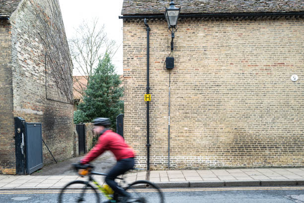 Blurred speeding cyclist seen traveling down a one way street. The distant shows medieval houses and a water hydrant yellow sign on a down pipe.