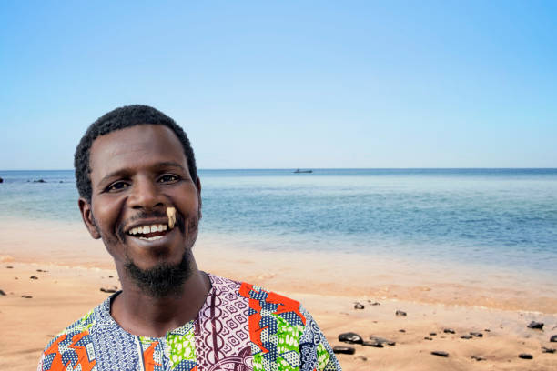 African man holding a miswak between his teeth at the beach (traditional teeth cleaning twig, also called sothio or sotio), photo