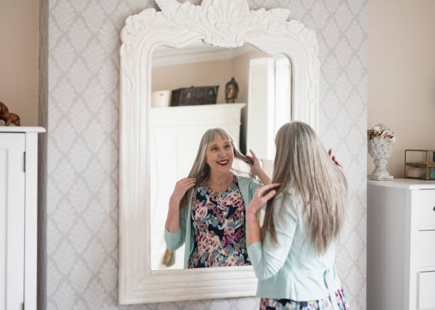 istock Smiling senior woman checking appearance in bedroom mirror 1467912883