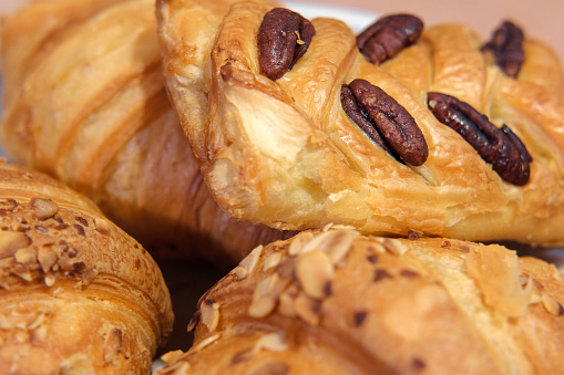 French puff pastry and croissant with toppings. Freshly baked sweet buns couple flaky pastry with almond nuts in a white plate for dessert. Delicious Breakfast or brunch concept. Burekas, turnovers. confectionery. Set of hot tasty crispy bakery products rotation on turntable