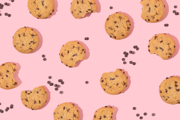 istock Creative pattern with cookies and chocolate chips on pastel pink background. Retro fashion aesthetic cookie concept. Minimal romantic idea. 1467913868