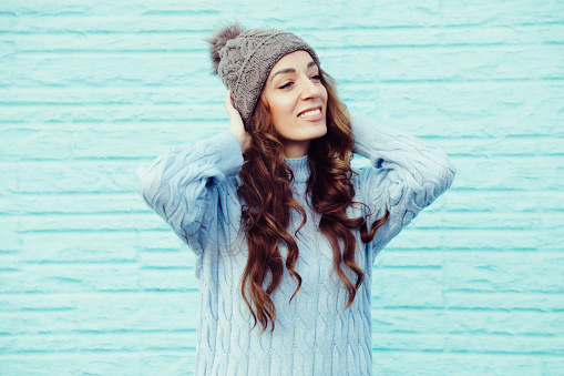 Portrait of smiling woman wearing hat and blue sweater on blue background
