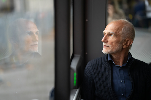 Senior man looking through window while sitting in bus.