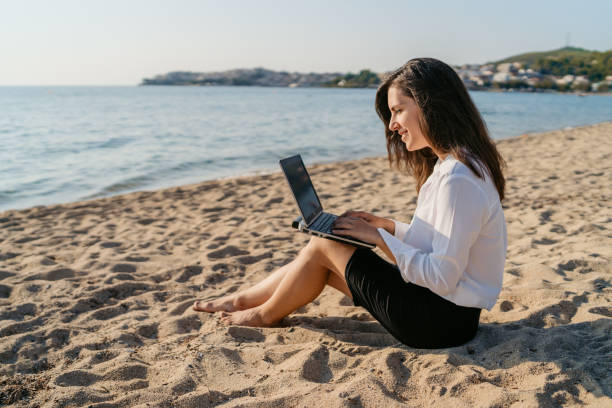 istock Young Woman Using Laptop On The Beach 1467916475