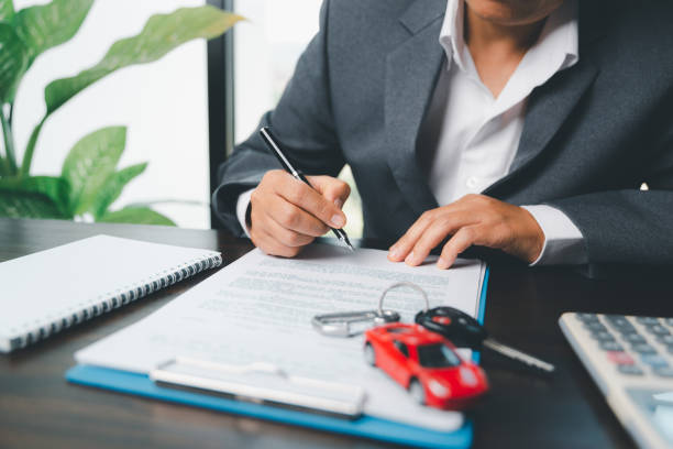 Car dealer business woman signing car insurance document or lease paper. Planning to manage transportation finance costs. Concept of car insurance business, saving buy with tax and loan for new car. stock photo