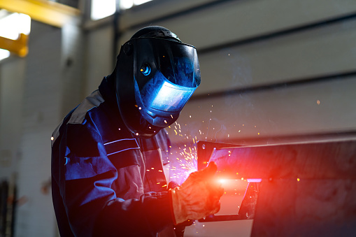 Metal working man welding in mask. Handymen perfoming welding at workplace.