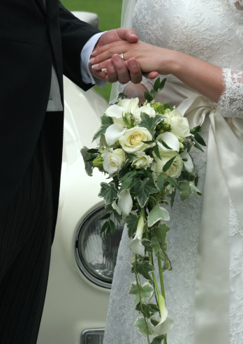 just married and holding hands , wth ring and flowers on show