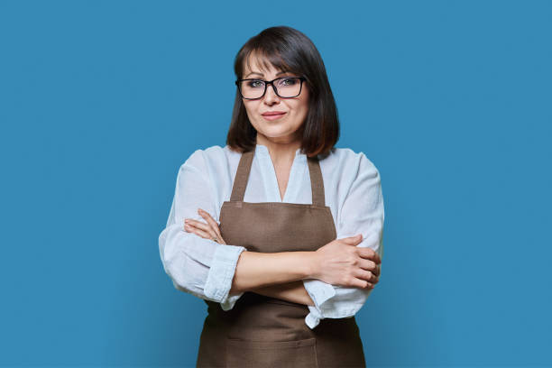 istock Confident middle aged woman in apron looking at camera on white background 1467923596