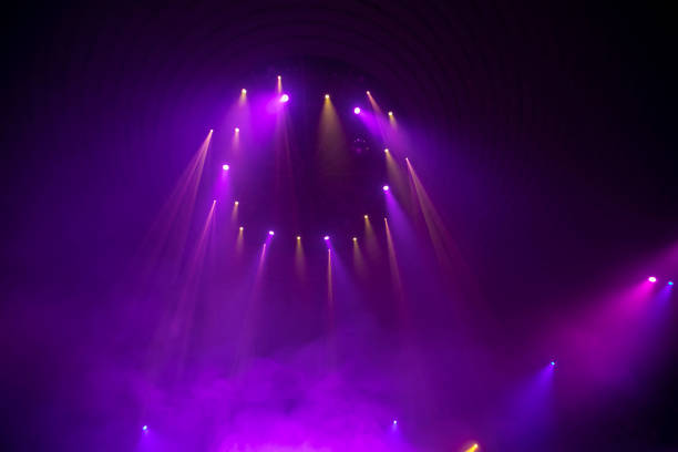 Purple rays from stage spotlights on a dark background.