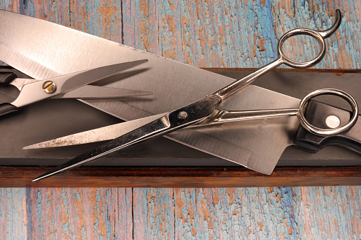 Sharp knife's blade on cutting board. Brushed stainless steel material
