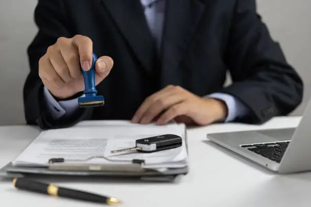 Photo of Businessman signing a contract for buying of selling a car.Car rental service. insurance, and contract agreement concepts