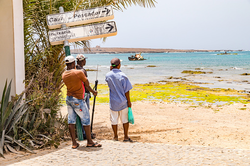 Three men at the harbor of Sal Rei look at the Atlantic Ocean, Boa Vista, Cape Verde Islands, March 29th, 2017