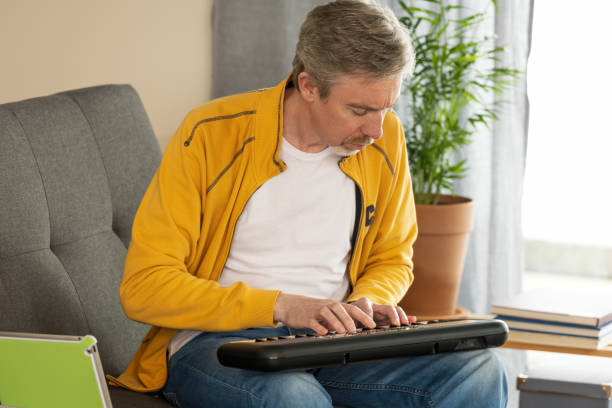 istock White 50 year old male learning to play synthesizer, using digital tablet 1467930036