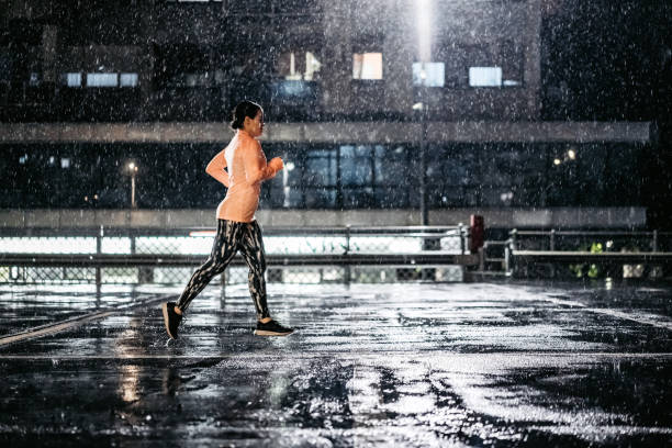 istock Young Woman Jogging Outdoors In The Rain At Night 1467930213