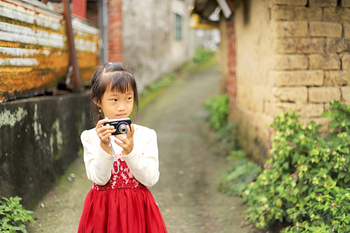 a Asian girl taking pictures in the alley next to the old house