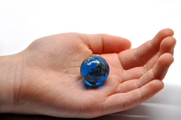 whole world in the palm of my hand a childs hand holding an earth marble isolated on a white background marble globe stock pictures, royalty-free photos & images