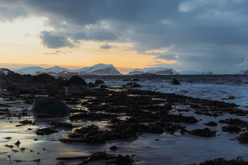 High-angle view of the beautiful frozen seashore with view of the snowcapped islands in bright sunset in Scandinavia