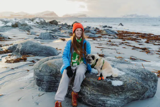 Photo of Happy woman having fun with a dog at the scenic winter beach in Norway