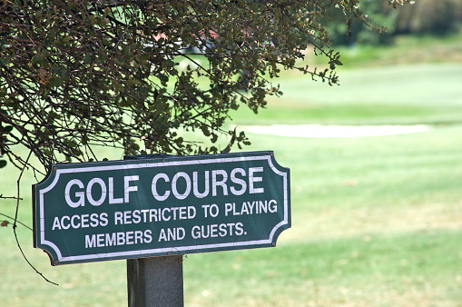 A small sign telling pedestrians that access to a golf course is \