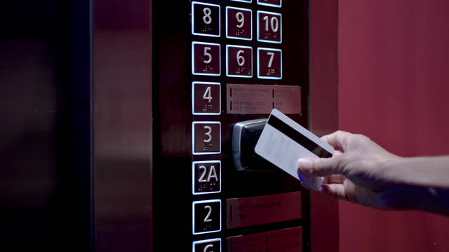Woman using proximity card, contactless digital key to unlock for use elevator in the hotel. Digital or keyless to authenticate.
