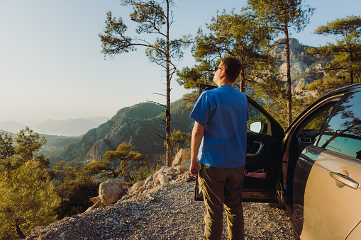 Silhouette of a male enjoying road trip in Mediterranean Turkey and relaxing at the rest stop with dramatic view of raw nature during bright sunset