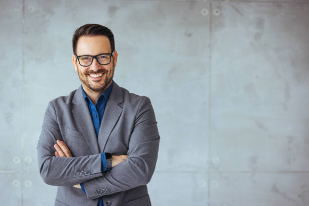 Portrait of young businessman wearing eyeglasses and standing outside conference room. stock photo