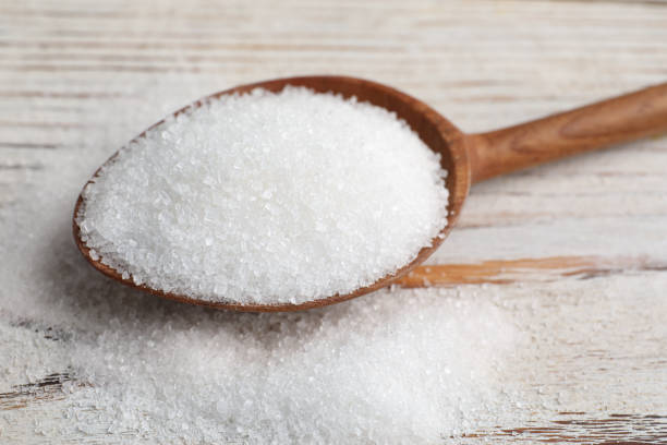 istock Spoon with granulated sugar on white wooden table, closeup 1467942453