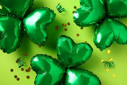 Happy Saint Patrick Day concept. Shamrock shaped balloons with confetti on green background