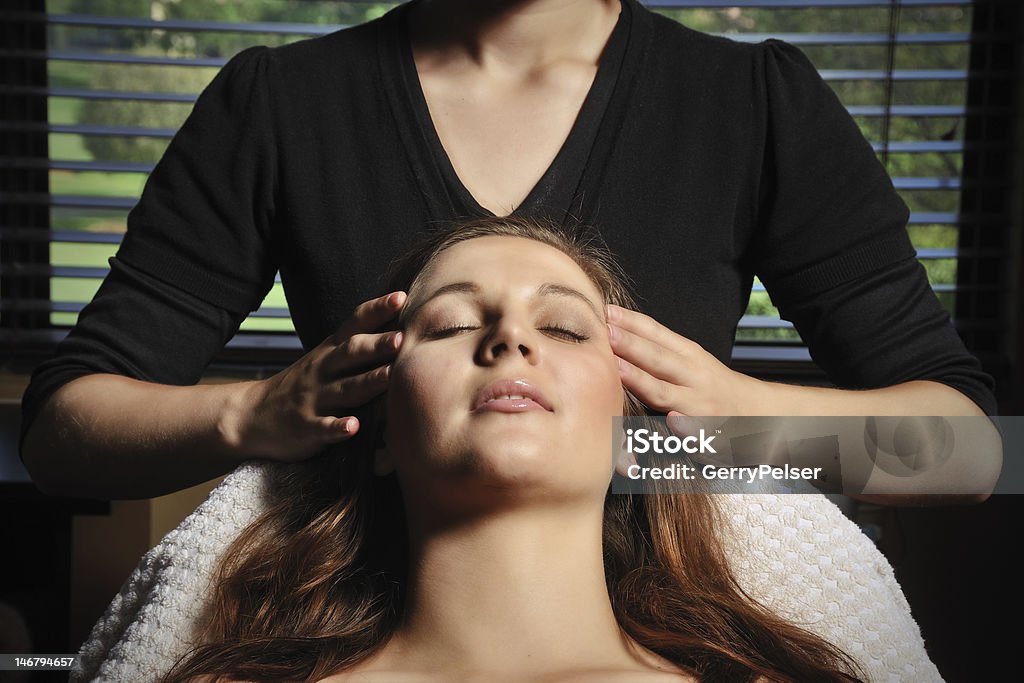 Jovem mulher com olhos fechados recebendo um tratamento facial - Foto de stock de Massagem de Cabeça royalty-free