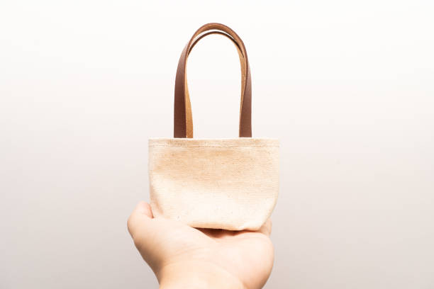 istock small full canvas bag with ties, Reusable eco bag. Empty small cotton bag with string on white background. 1467947200