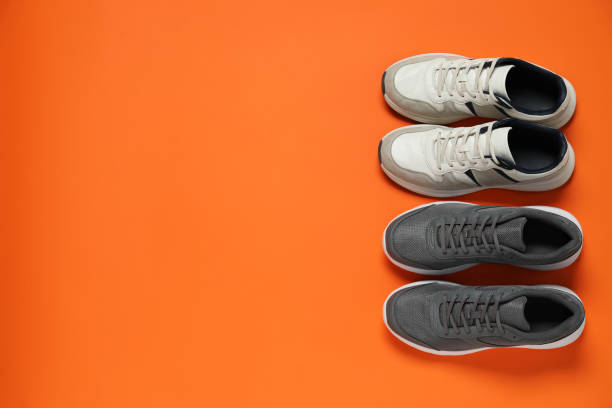 istock Different stylish sport shoes on orange background, flat lay. Space for text 1467949539