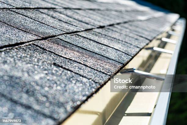 Closeup Of A Newly Installed Shingled Roof And Seamless Aluminum Rain Gutters Stock Photo - Download Image Now