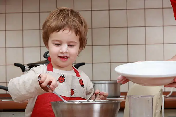 Young "cook" preparing food with food processor in the home kitchen. Boy's nose covered with flour.