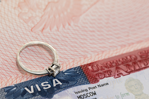 A ring with a precious stone on the background of a US visa as a symbol of engagement.