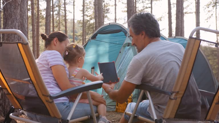 Family camping in nature at sunset. Tent in woods.