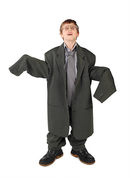 Boy in big grey man's suit, boots and glasses isolated stock photo