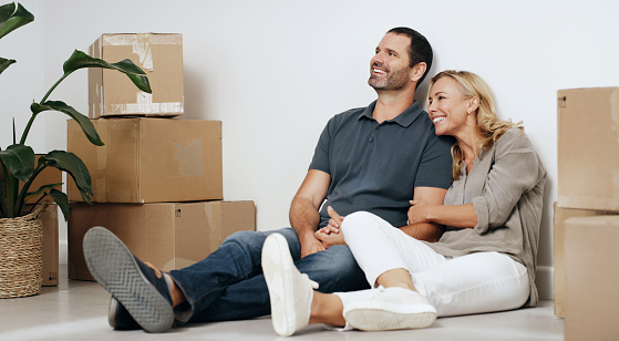 Moving, boxes and couple relax on floor with room planning, happy with real estate and property investment. Mature people or woman with partner thinking of finance success for apartment or house
