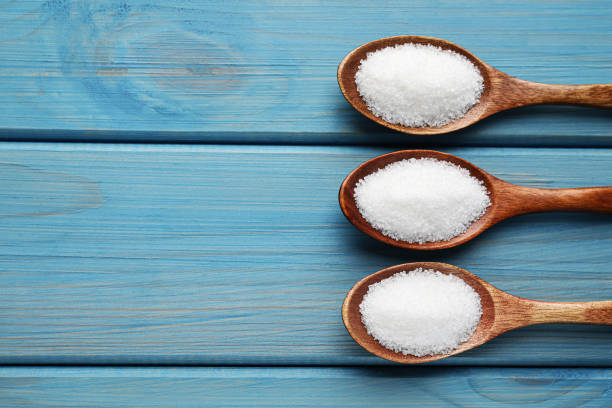 istock Granulated sugar in spoons on turquoise wooden table, flat lay. Space for text 1467960578
