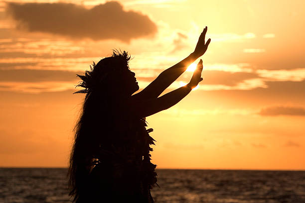 Hula girl reaches for the sun This Hawaiian hula dancer performs a hula in front of the tropical sunset. maui stock pictures, royalty-free photos & images