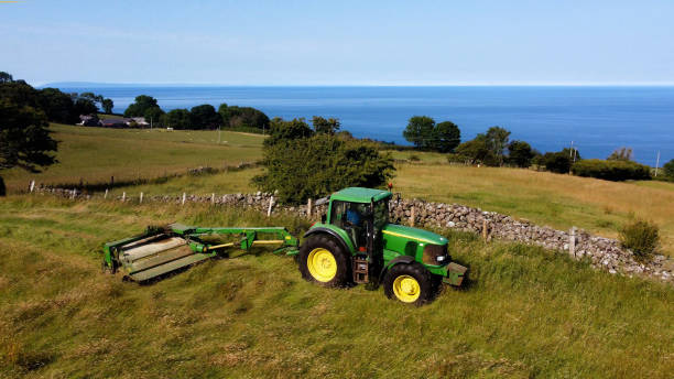 john deere 6920 tracteur et tondeuse coupant de l’herbe pour l’ensilage dans une ferme au royaume-uni - tractor farm uk agriculture photos et images de collection