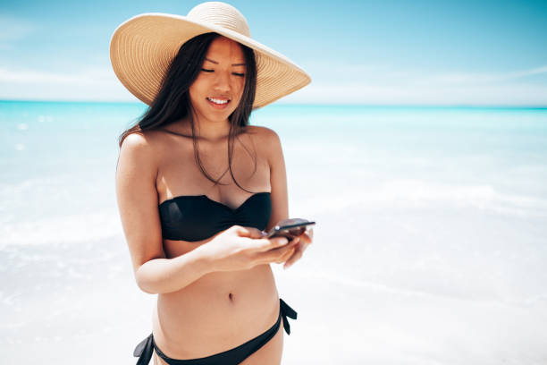 istock asian woman text messaging on the beach 1467965194