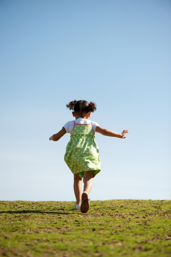 Little girl having fun running up a hill.